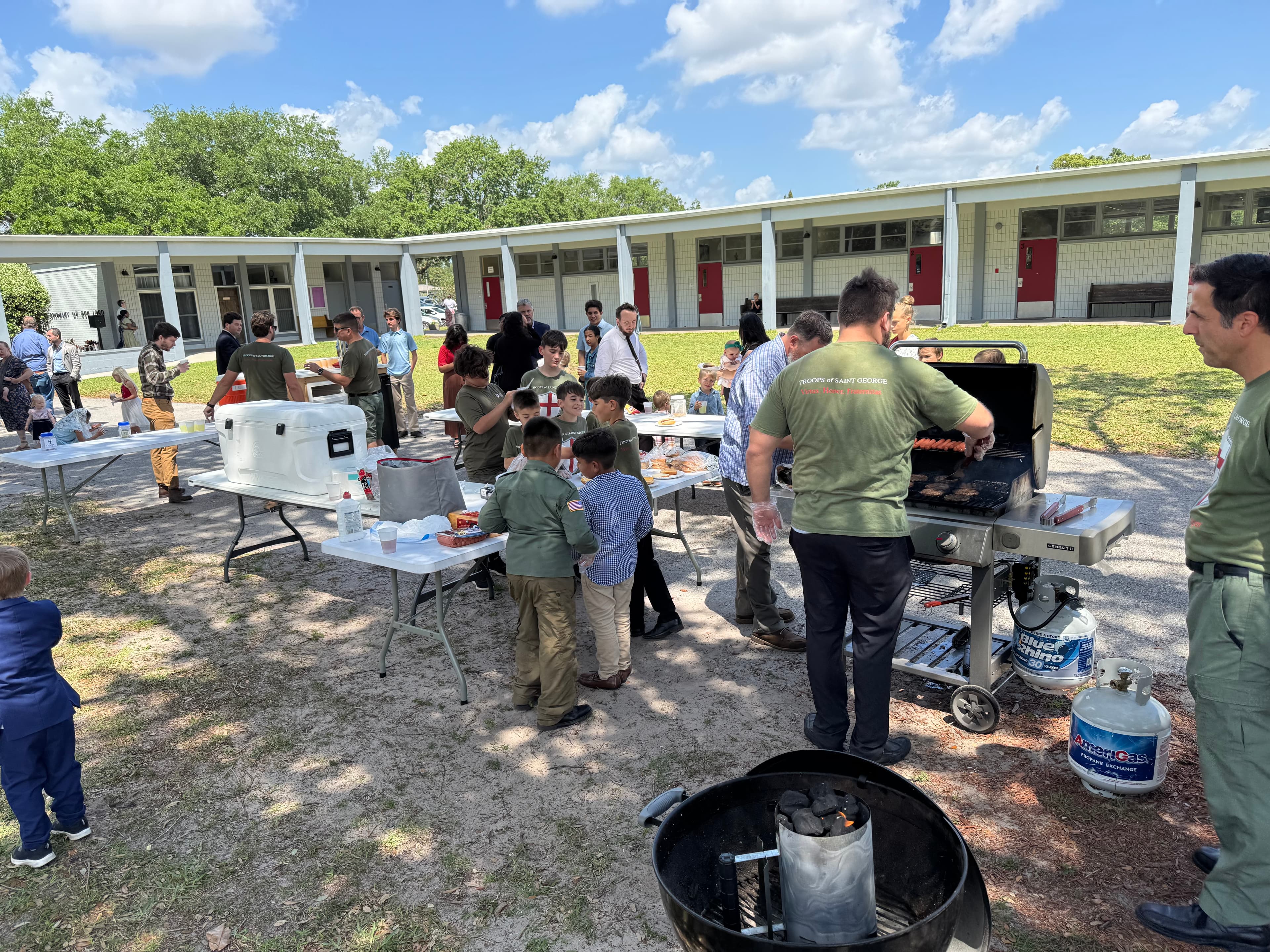 Troop families gathered around the grill outdoors